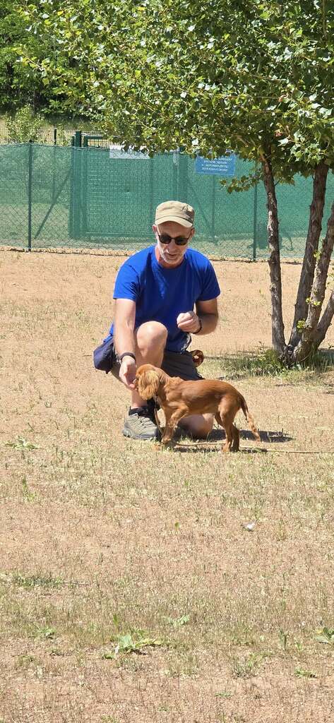 Adhérent accroupi avec un petit chien sur le terrain